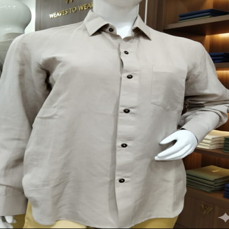 Mannequin wearing a beige shirt with black buttons in a store setting.